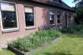 Vooraanzicht van de vakantiewoning met ruime tuin en kruidentuin